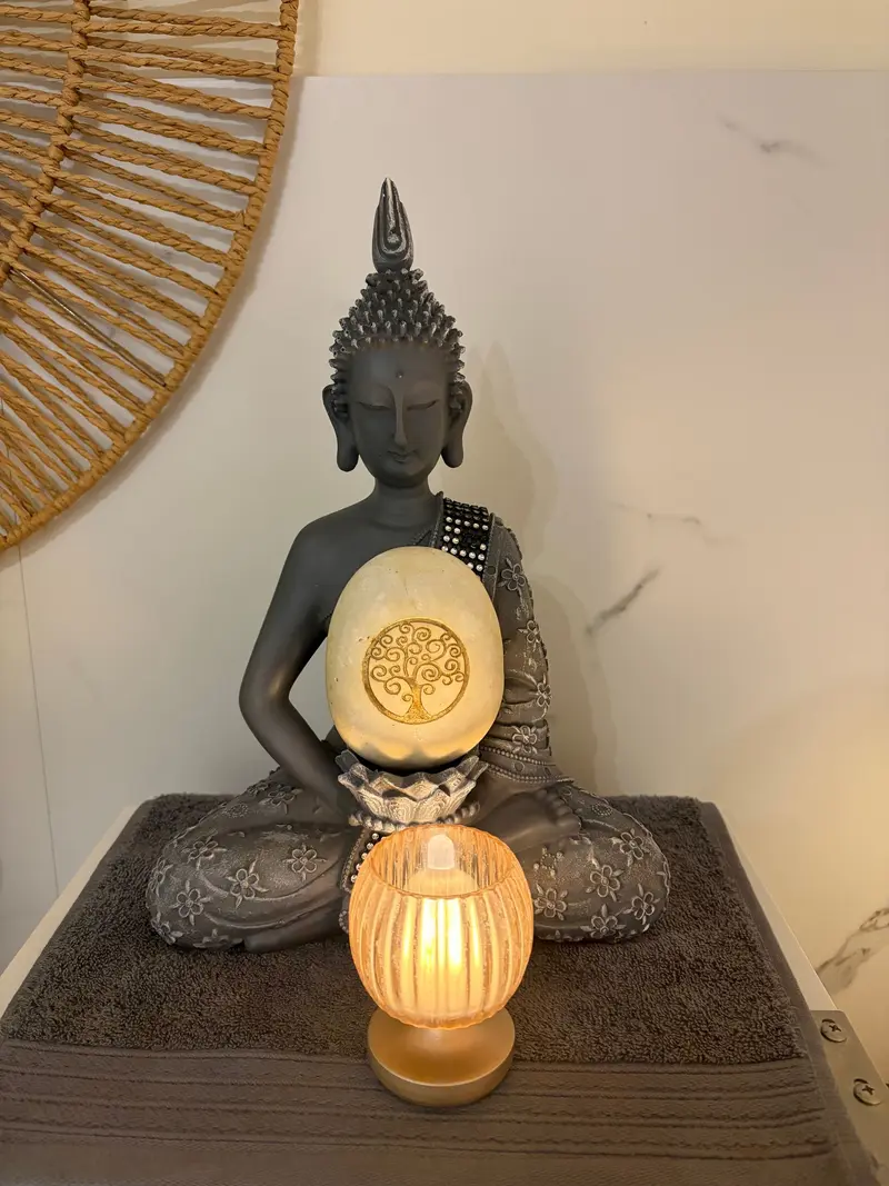 Bouddha tenant une lampe allumée, posé sur la table